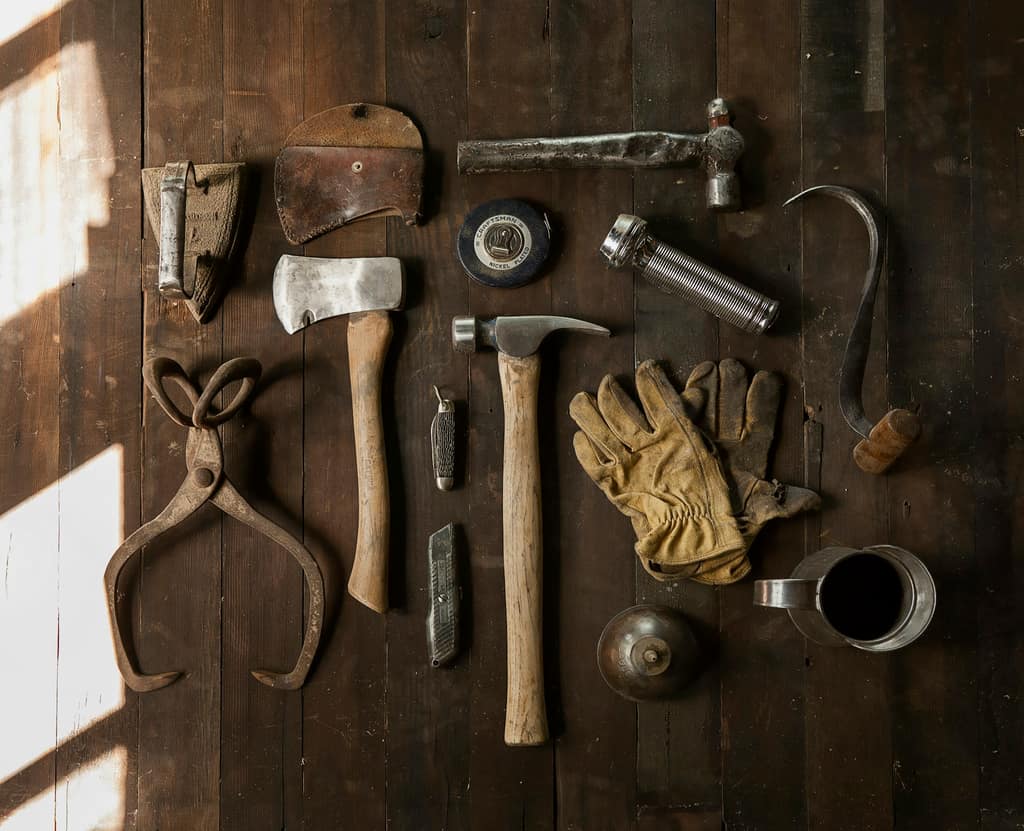 Garden hand tools resting on soil, representing careful, hands-on garden work.